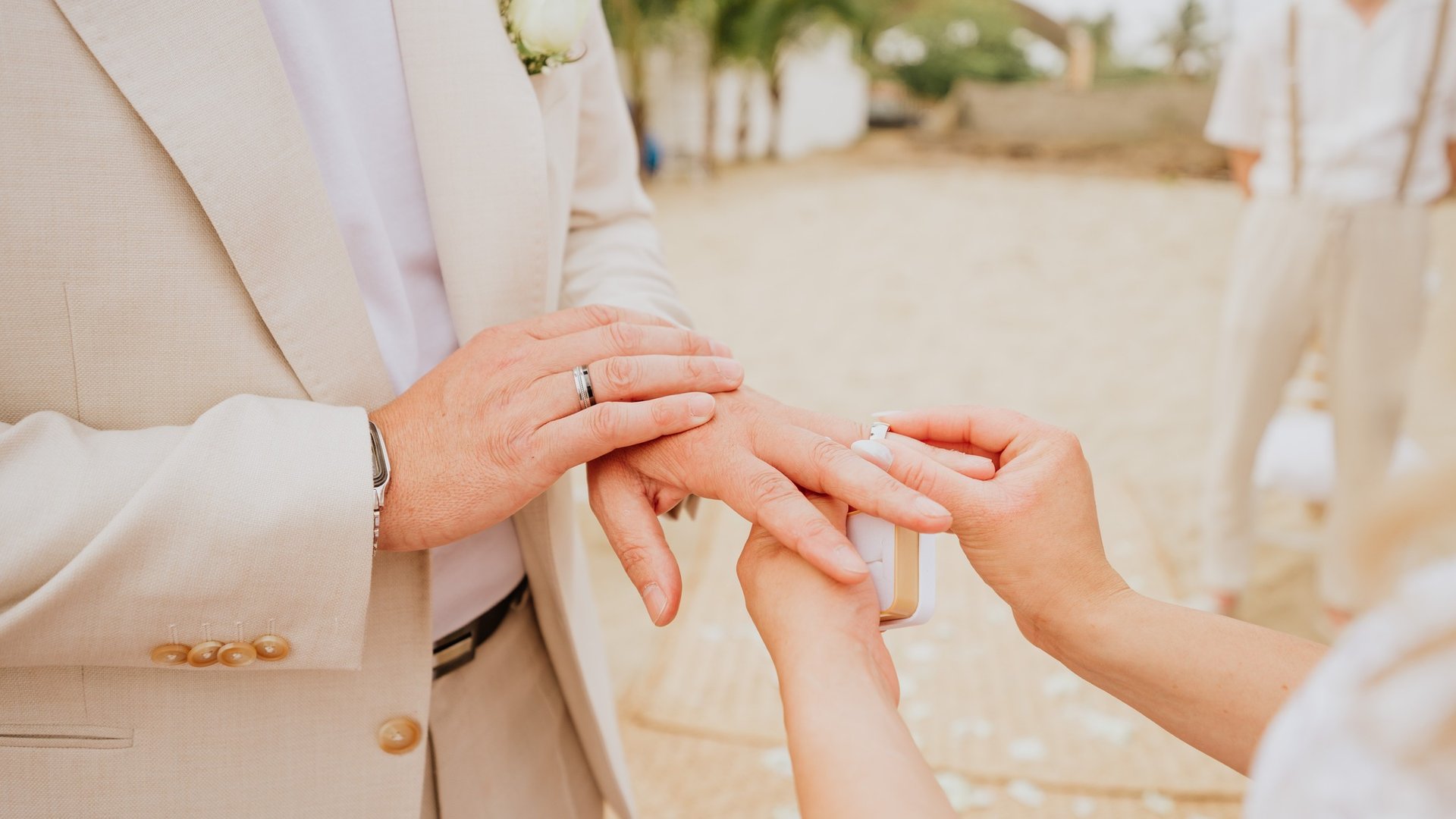 Intercambio de anillos en ceremonia de boda frente a playa con palmeras tropicales