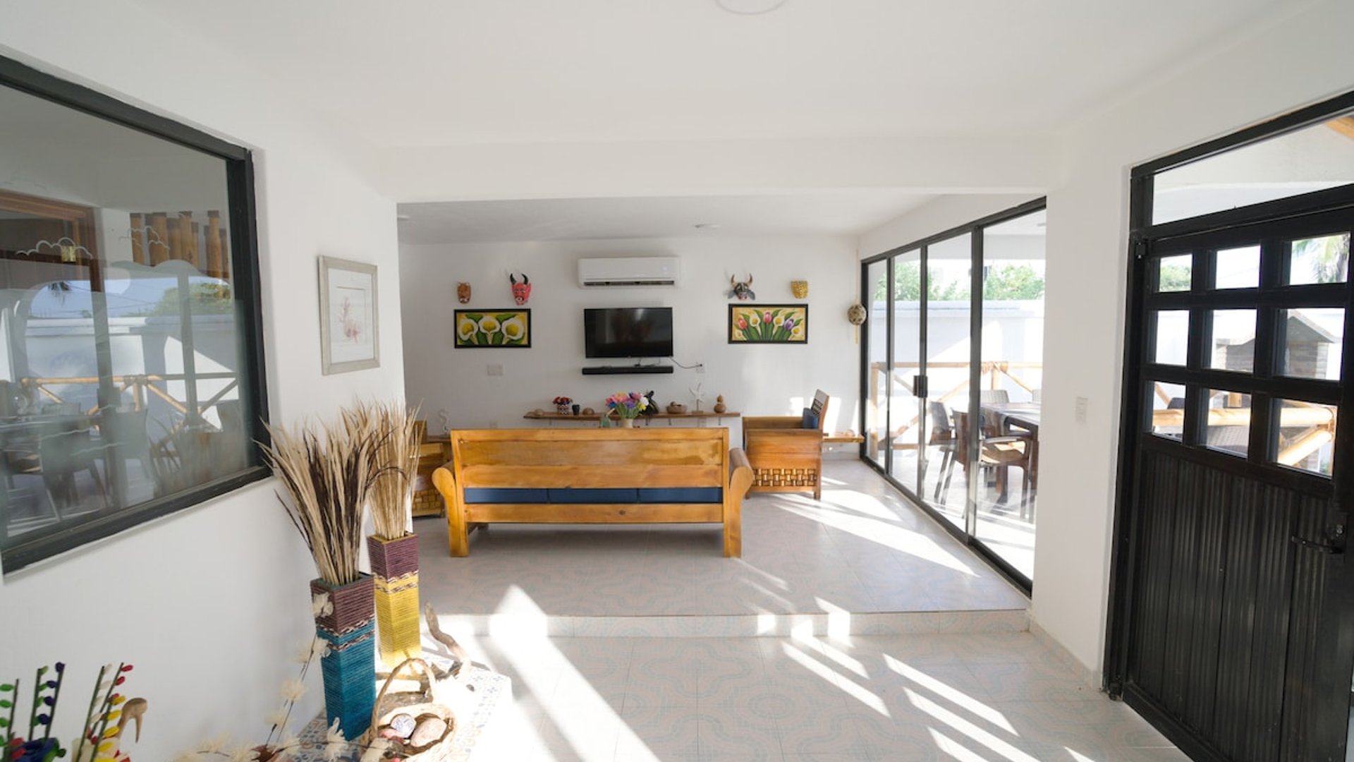 Sala amplia y luminosa con muebles de madera, arte artesanal en paredes y acceso a terraza exterior