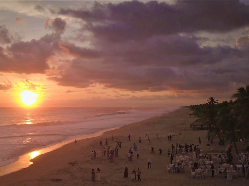 Beach banquet at sunset with a large group celebrating by the sea