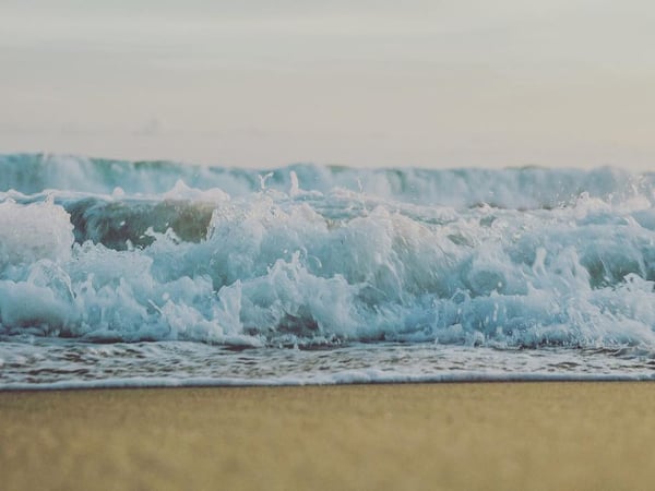 Olas turquesas rompiendo sobre la orilla de arena en la costa del Pacífico, atmósfera serena y luz difusa