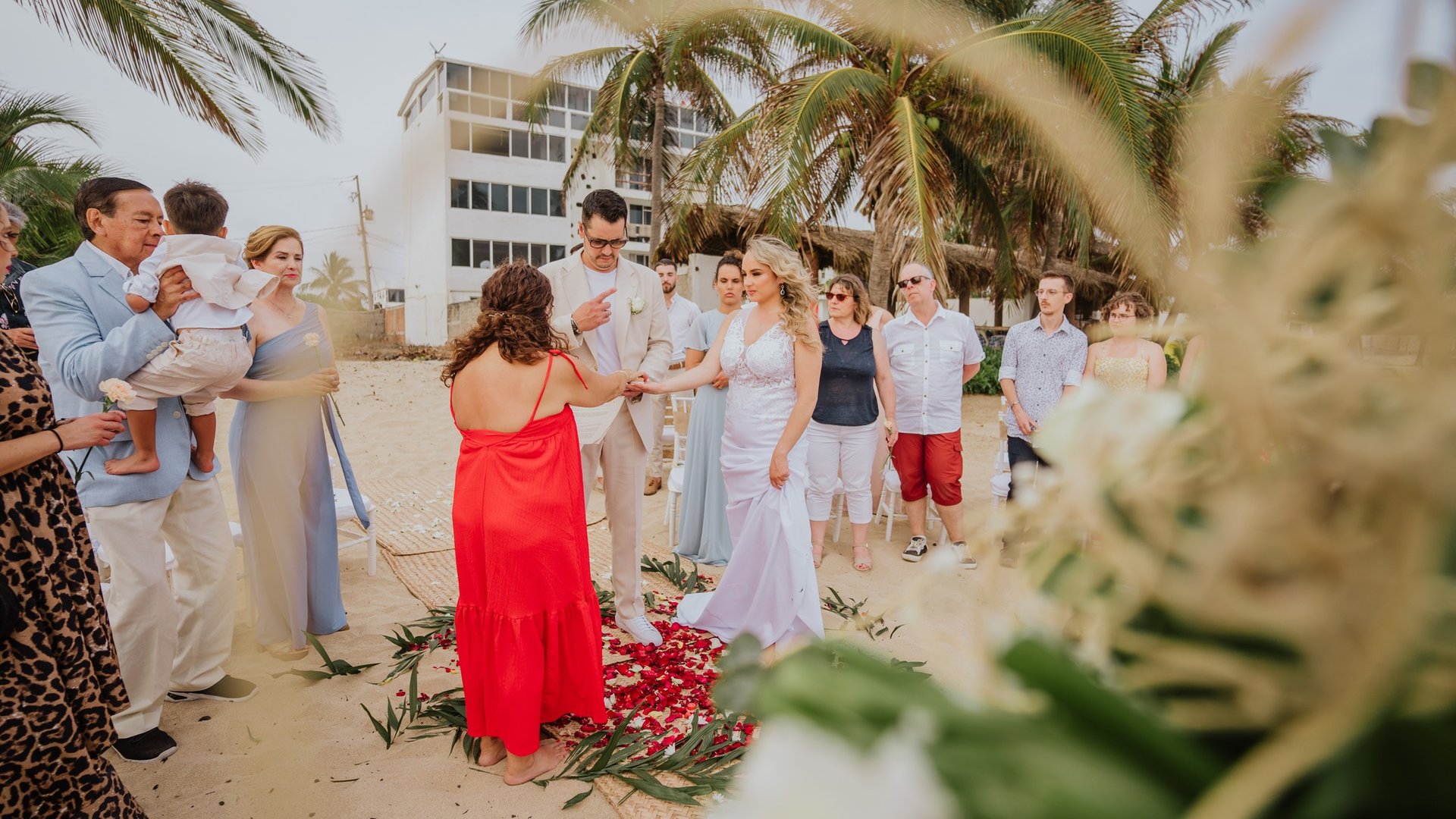 Ceremonia de boda en playa con pasillo decorado con pétalos rojos y palmeras tropicales