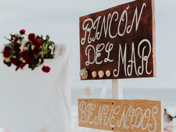 Letrero de bienvenida de Rincón del Mar con decoración floral de rosas rojas y vista al mar de fondo