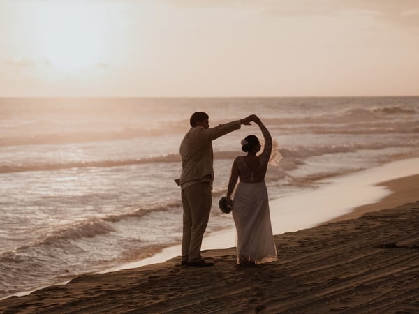 Sesión de boda en playa del Pacífico al atardecer con olas doradas de fondo