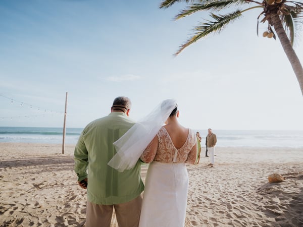 Ceremonia de boda íntima en playa con palmeras y vista al océano Pacífico al atardecer