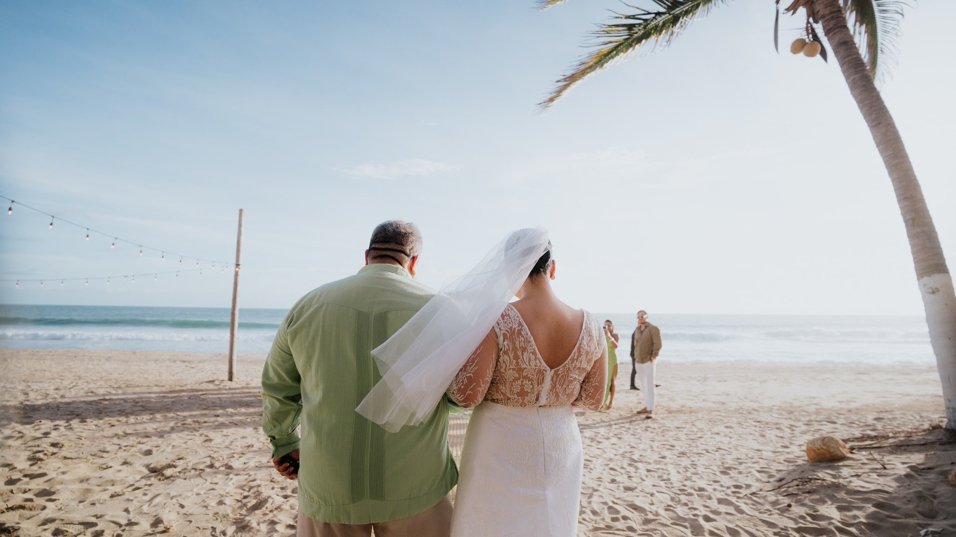 Ceremonia de boda íntima en playa con palmeras y vista al océano Pacífico al atardecer