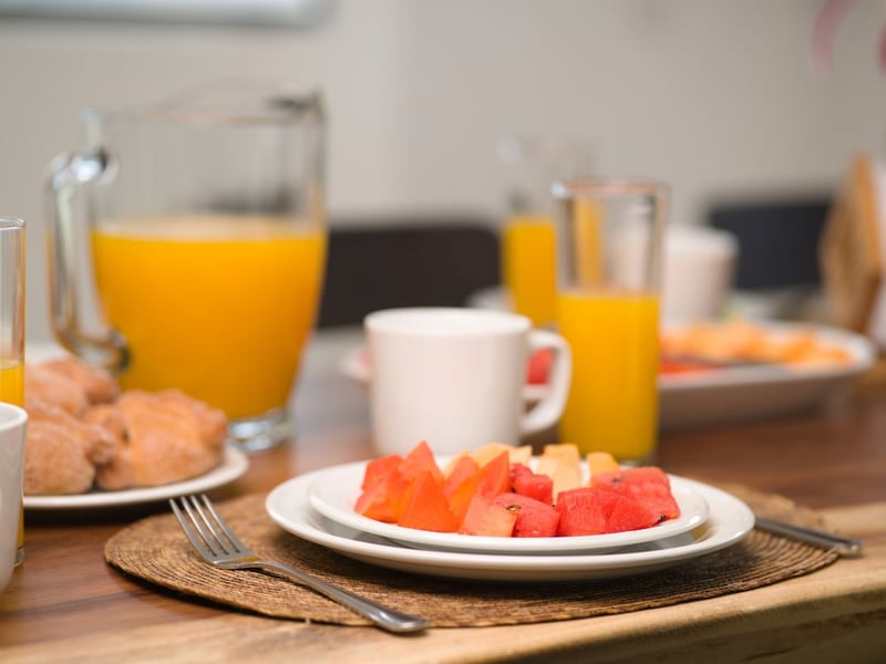 Plate of fresh fruit, orange juice and sweet bread on a wooden table