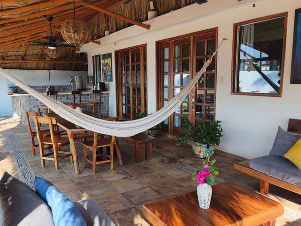 Terraza con palapa, hamaca, sala y comedor exterior con cocina de mosaicos talavera al fondo