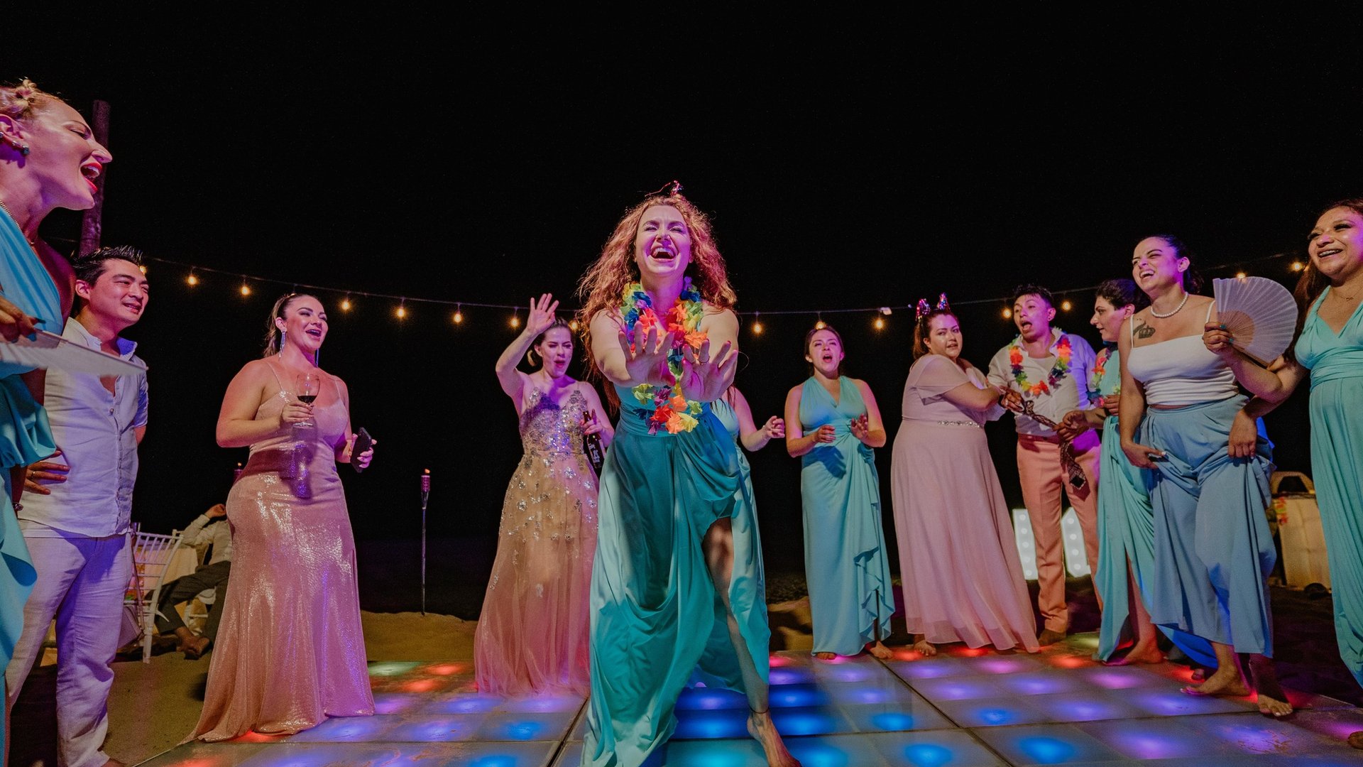 Fiesta nocturna de boda en pista iluminada con luces de colores y guirnaldas colgantes