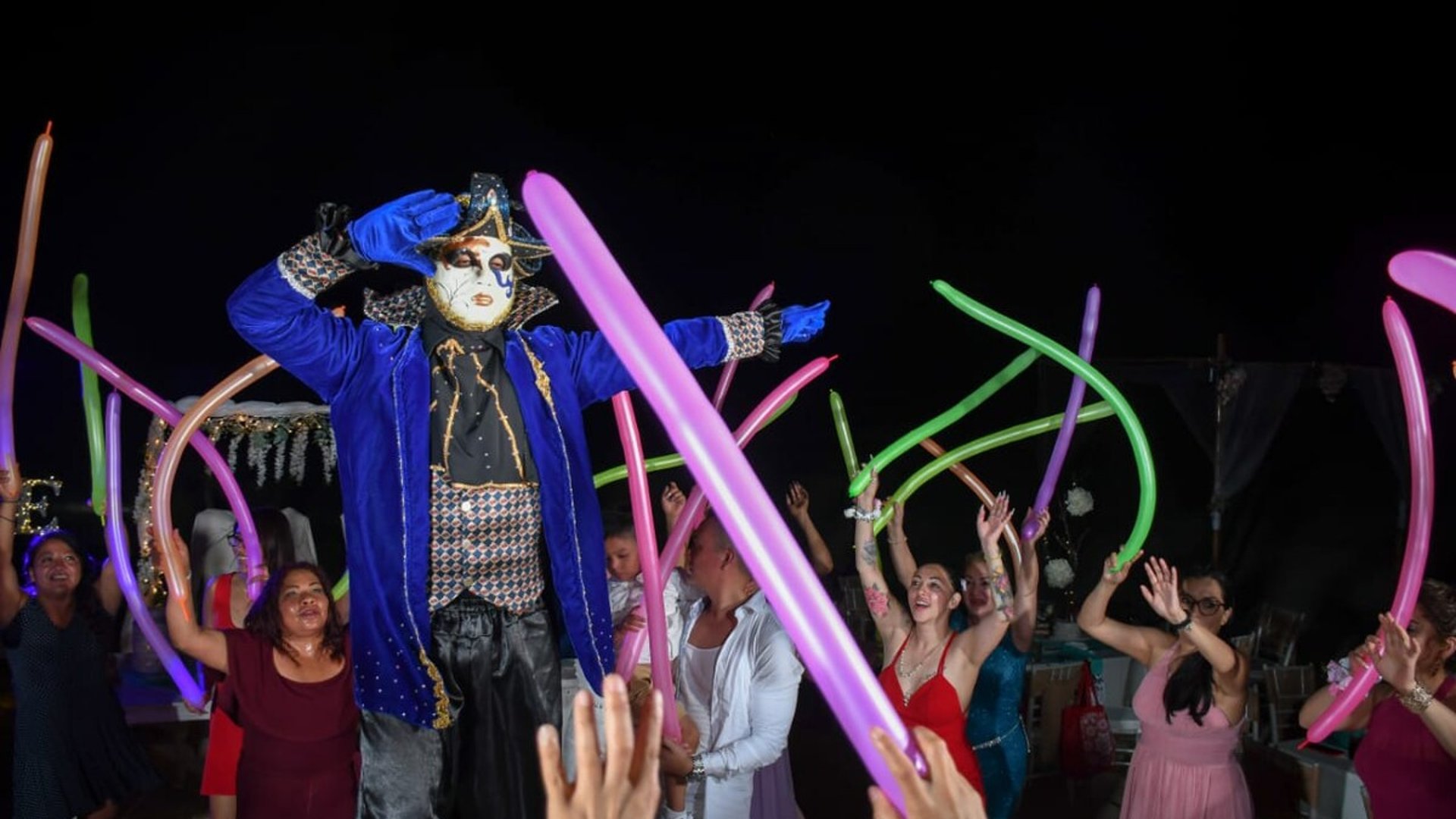 Animación nocturna en evento con personaje disfrazado y globos de colores entre los invitados