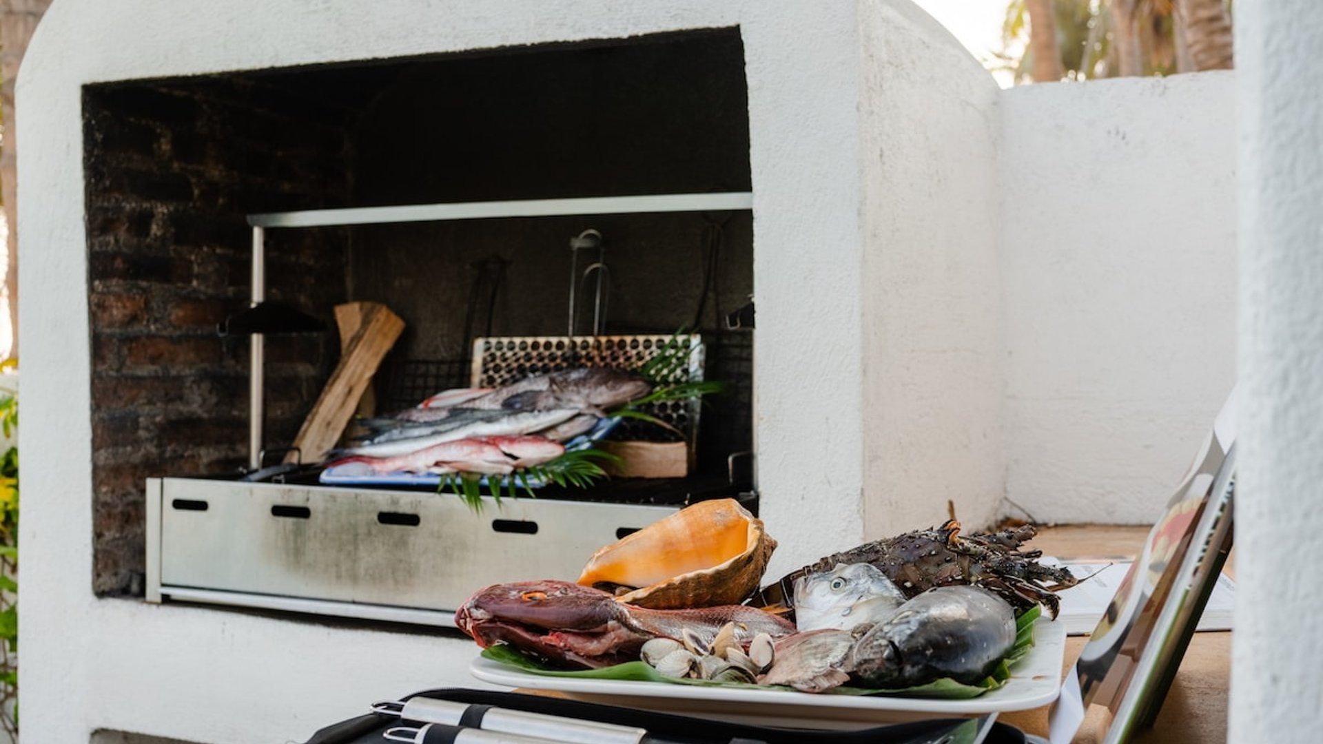 Asador exterior de ladrillo con pescados y mariscos frescos listos para cocinar al aire libre