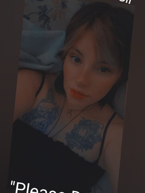 Close-up selfie of a young woman with brunette hair lying down, wearing a top with tattoos visible on her chest, surrounded by overlaid text phrases.