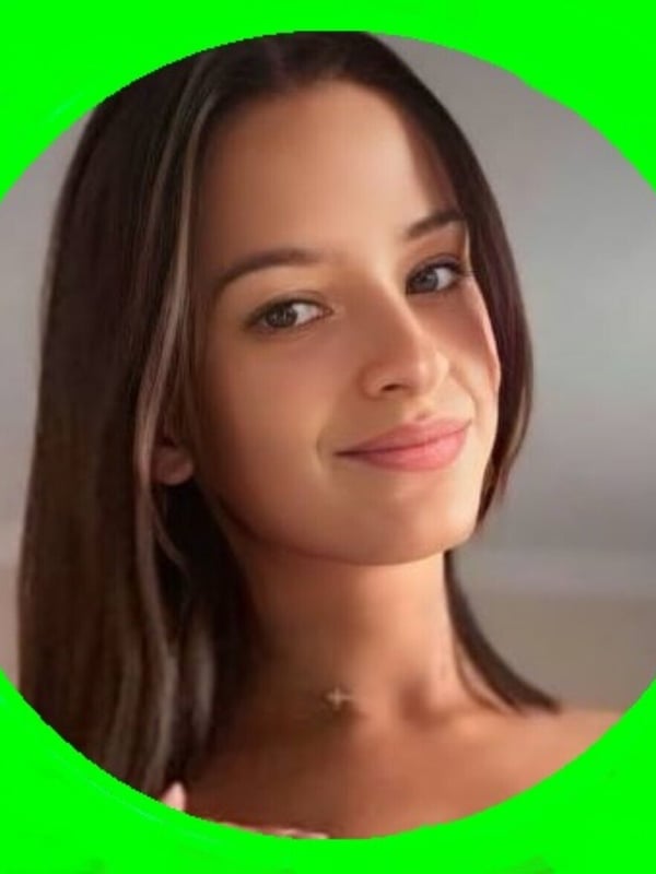 Close-up portrait of a young woman with brown hair and green eyes smiling softly against a green background.