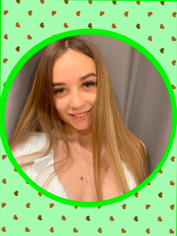 A smiling young woman with long brown hair, wearing a white top, framed in a green circle with heart patterns.