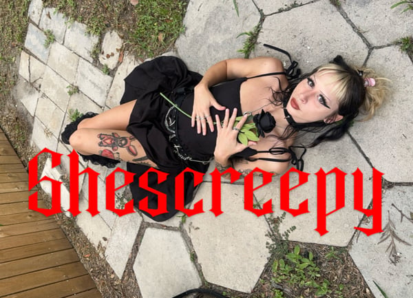 A woman in gothic attire with black dress and dramatic makeup poses on a stone patio surrounded by greenery, holding a rose, with bold text overlay.