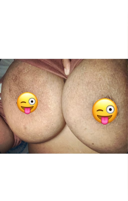 Close-up of a woman's chest in a pink top with yellow emoji stickers placed on the skin.