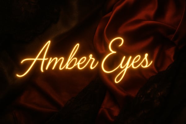 Glowing neon text reading 'Amber Eyes' displayed over a dark red fabric background.