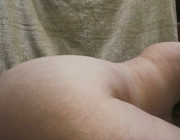 Close-up view of a person's curvaceous figure in soft lighting against a neutral background.