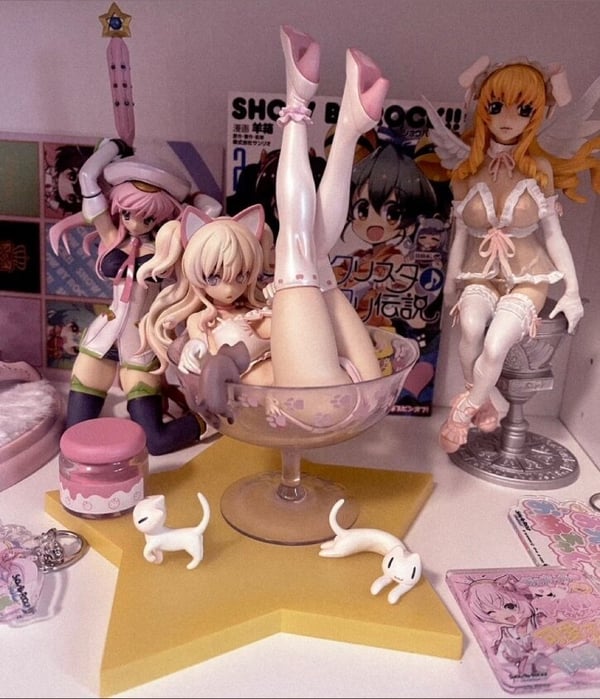 Display of anime figurines in lingerie-style outfits posed on a shelf with pink decorations and a glass bowl in a bedroom setting.