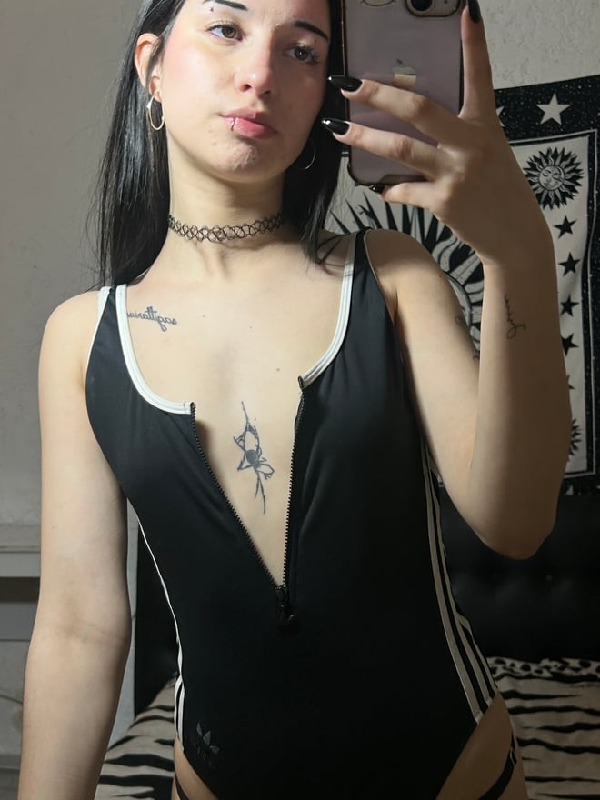 A person with dark hair taking a selfie in a bedroom setting.
