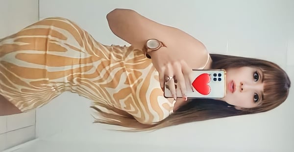 Young woman in a form-fitting zebra print dress posing confidently in front of a mirror while holding her phone.
