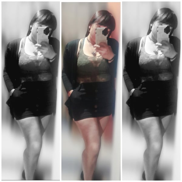 Young woman in black and white selfies, wearing a cardigan over a top and short skirt, posing confidently with her phone.