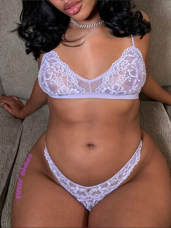 A woman posing confidently on a couch in delicate lace lingerie, showcasing her figure.