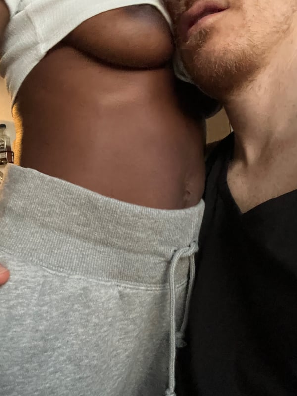 A woman in a white top and gray pants posing closely with a man in a dark shirt.