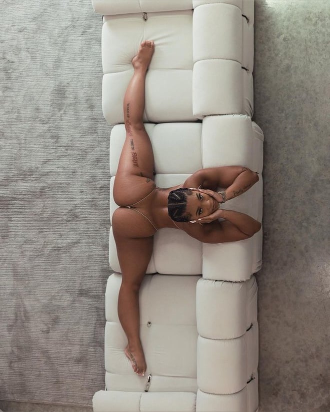 A woman posing flexibly on white modular furniture in a modern indoor setting.