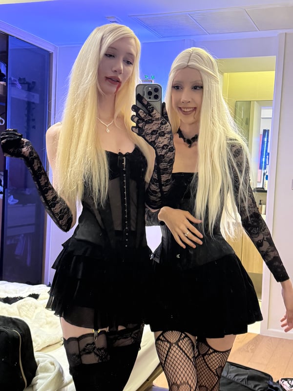 Two people posing together in casual clothing indoors, one wearing light-colored thigh-high stockings.