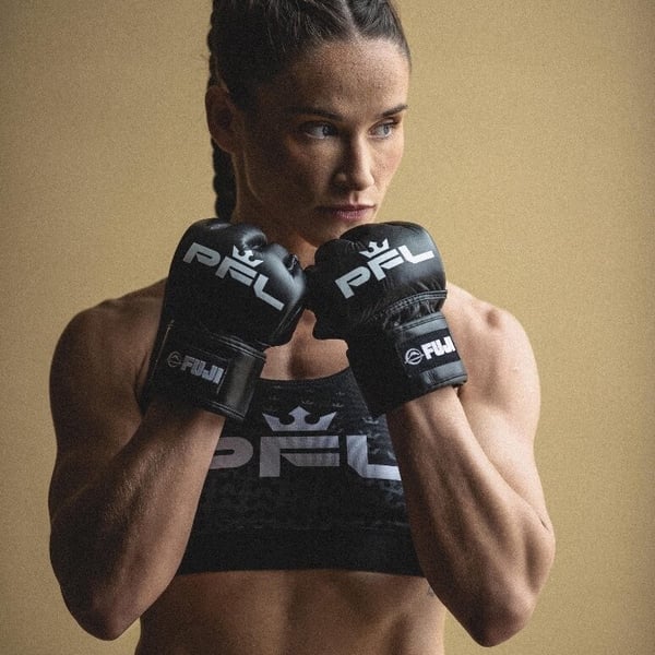 Female MMA fighter posing with gloves raised in a fighting stance, wearing a black sports top and PFL-branded gear against a neutral background.