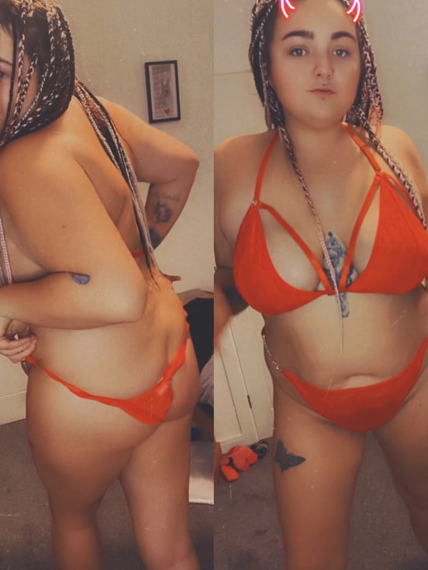 A woman with braided hair and cat ear headbands posing confidently in a red strappy swimsuit inside a room with casual decor.
