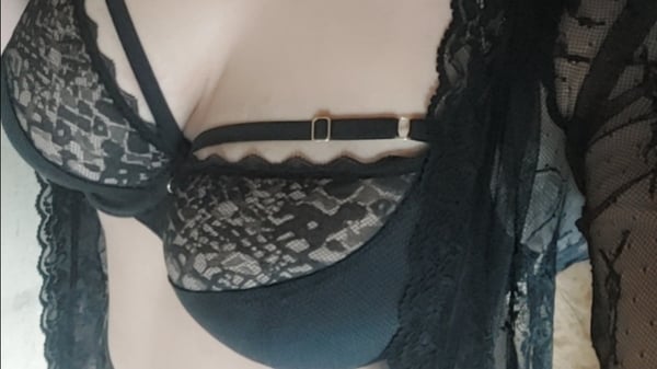 Close-up of a woman in elegant black lace lingerie, posing confidently with lace details and straps.