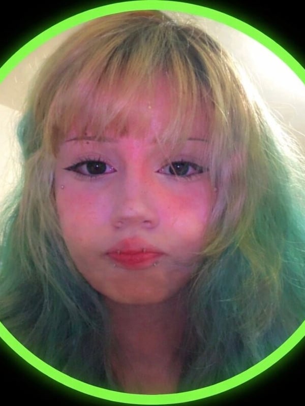 Close-up portrait of a young woman with multicolored hair and facial piercings.