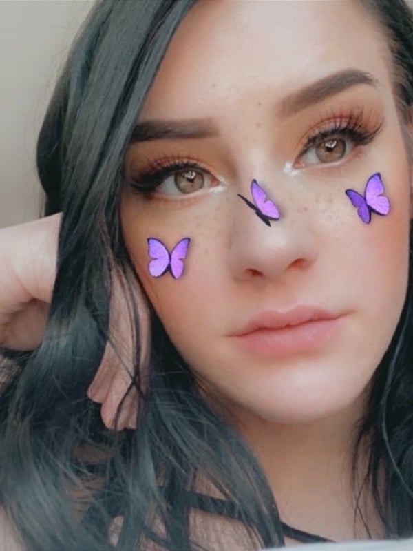 A young woman with dark hair and subtle makeup, featuring butterfly filters on her face.