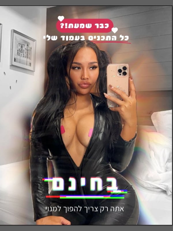A woman taking a selfie in a black leather outfit inside a room with Hebrew text overlays.