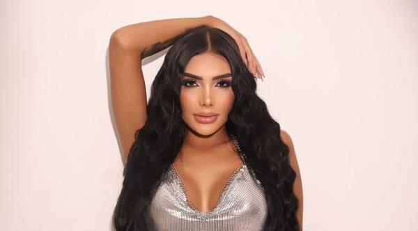 A person posing in a silver sequined top against a plain white background.