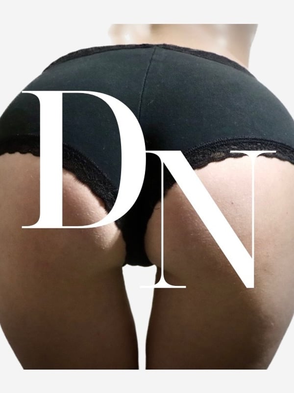 Close-up view of a person's lower body in black lace underwear, overlaid with large white 'DN' lettering.