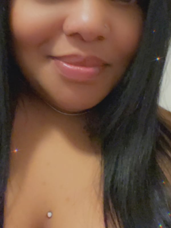 Close-up portrait of a woman with long dark hair, nose piercing, and subtle sparkle effects.