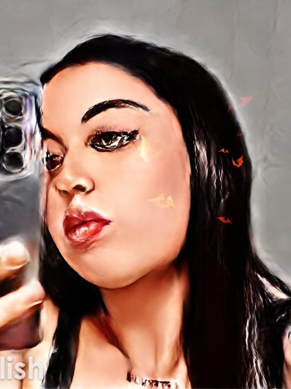 Close-up portrait of a woman with long dark hair, striking makeup, and glossy lips, holding a phone.
