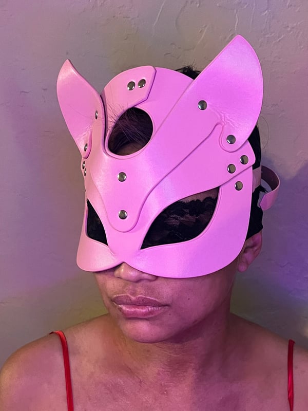 Person wearing a pink cat mask with lace details, posing against a plain background.
