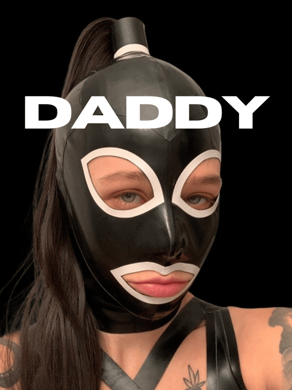 Close-up of a woman wearing a black latex mask and outfit with tattoos visible, overlaid with bold 'DADDY' text on a dark background.
