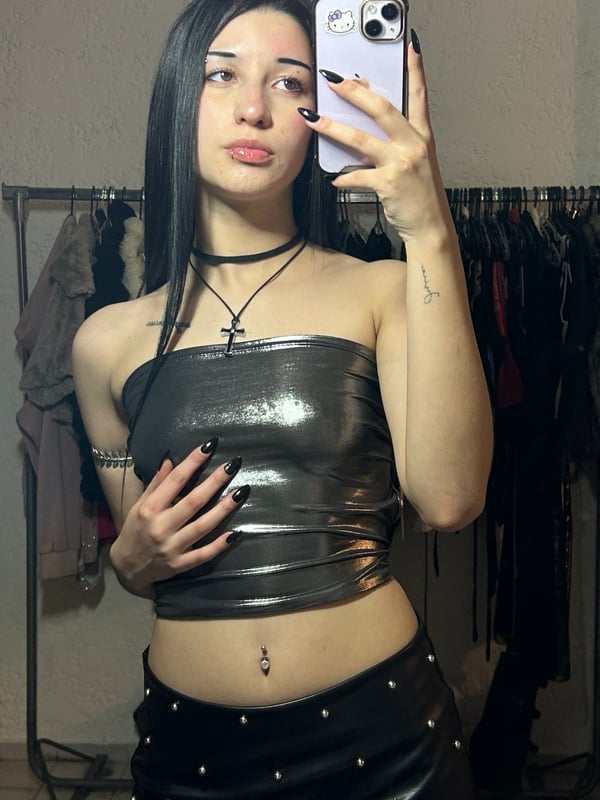 A person with dark hair taking a selfie in a bedroom setting.