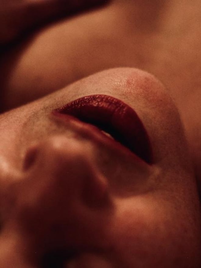 Close-up portrait of a woman with full red lips and warm skin tones, captured in a soft-focus artistic style.