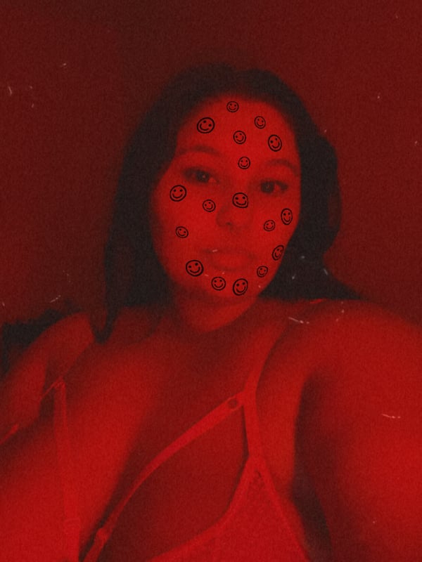 Close-up portrait of a woman with face paint dots wearing a red top against a red background.