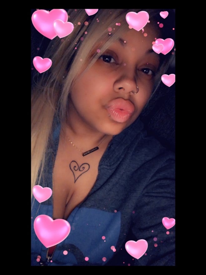 Close-up selfie of a woman with blonde hair and pink heart filters, puckering her lips playfully.