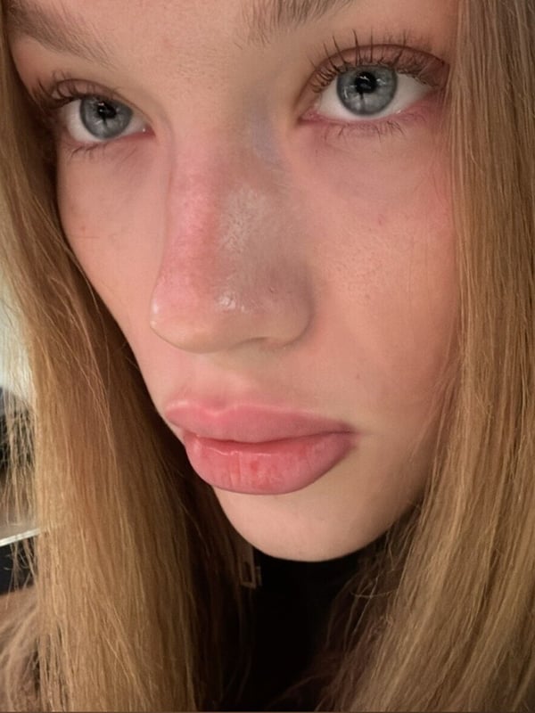 Close-up selfie of a young woman with long light brown hair and blue eyes.