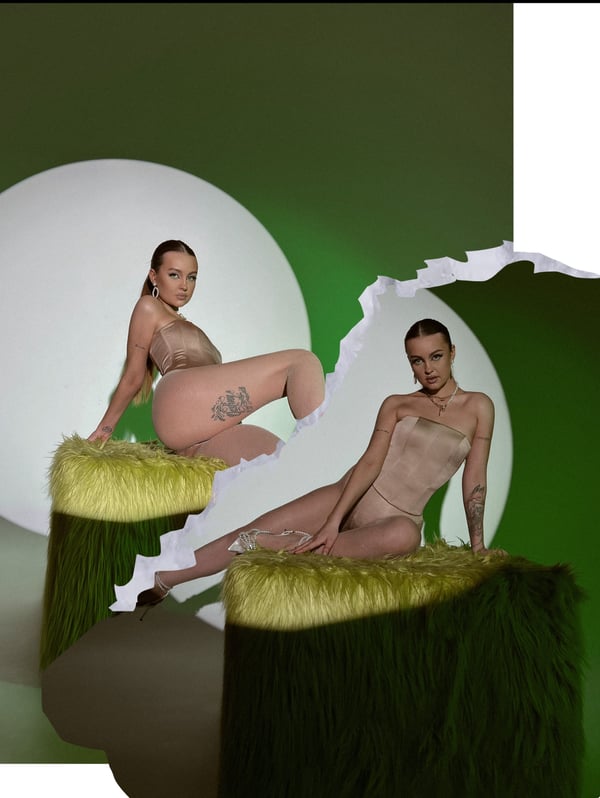 Two women posing in form-fitting outfits on green furry stools against a green background with white circular elements.