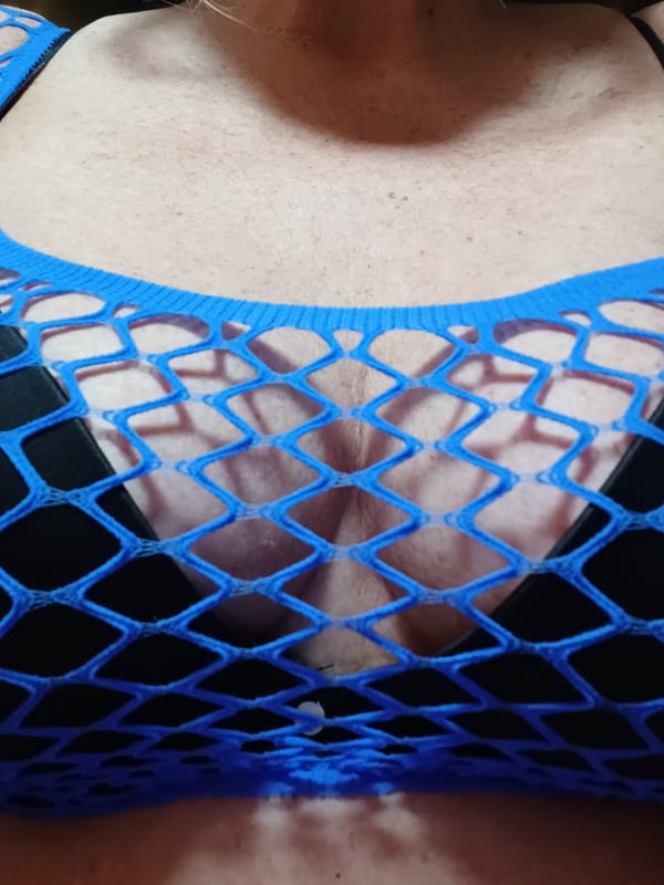 Close-up of a woman in a blue mesh top posing confidently.