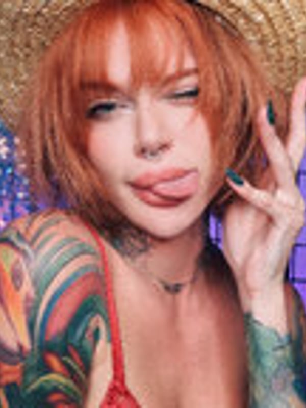 Close-up portrait of a model in a blue-haired cosplay outfit with cat ears, posing with neon lighting.