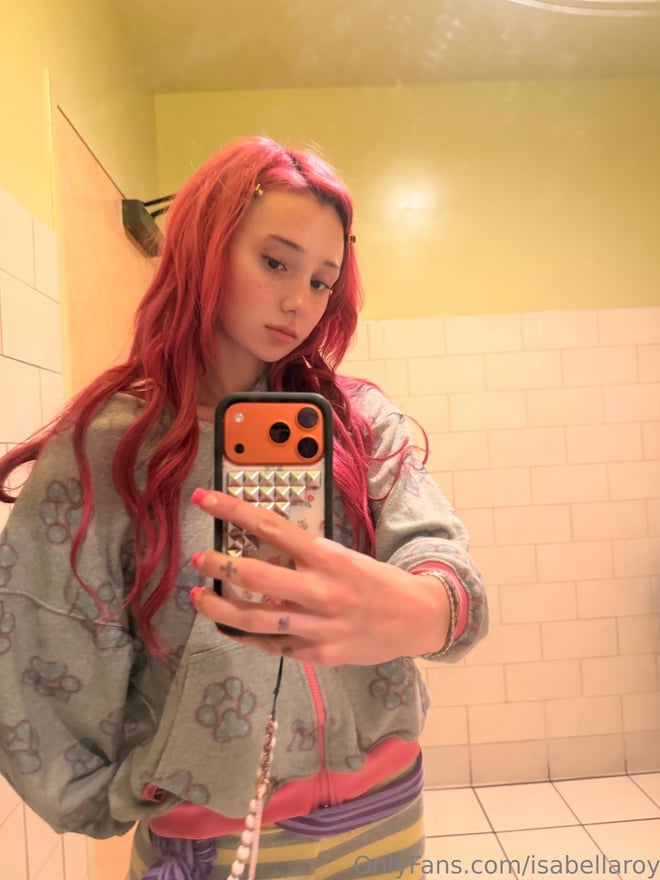A young woman with long brown hair taking a mirror selfie indoors, wearing dark lingerie.